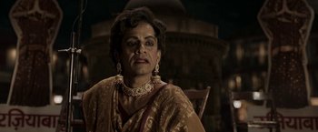 Movie still from “Gangubai Kathiawadi” (2022), directed by Sanjay Leela Bhansali – An older woman wearing a gold and red sari; Close Up shot, Over the shoulder angle