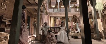 Movie still from “Gangubai Kathiawadi” (2022), directed by Sanjay Leela Bhansali – Two women and a man sitting on a bench in a room; Wide shot, Low angle