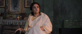 Movie still from “Gangubai Kathiawadi” (2022), directed by Sanjay Leela Bhansali – A woman sitting on a chair wearing a white robe; Medium shot, Low angle