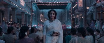 Movie still from “Gangubai Kathiawadi” (2022), directed by Sanjay Leela Bhansali – A woman in a white sari is standing in front of an audience; Medium shot, Low angle