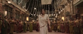 Movie still from “Gangubai Kathiawadi” (2022), directed by Sanjay Leela Bhansali – A group of women dressed in traditional garb in front of a crowd of onlookers; Wide shot, Low angle