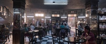Movie still from “Gangubai Kathiawadi” (2022), directed by Sanjay Leela Bhansali – People are sitting at tables in an old fashioned restaurant; Extreme Wide shot, High angle