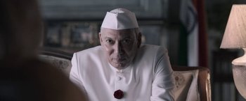 Movie still from “Gangubai Kathiawadi” (2022), directed by Sanjay Leela Bhansali – A man in a white suit and a red rose in his mouth; Close Up shot, Low angle