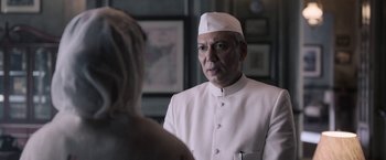 Movie still from “Gangubai Kathiawadi” (2022), directed by Sanjay Leela Bhansali – A man wearing a white hat looking into a mirror; Medium shot, Low angle