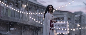 Movie still from “Gangubai Kathiawadi” (2022), directed by Sanjay Leela Bhansali – A woman in a white dress standing in front of lights; Wide shot, Low angle