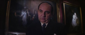 Movie still from “Neruda” (2016), directed by Pablo Larraín – A person wearing a suit and tie; Close Up shot, Low angle