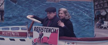 Movie still from “Neruda” (2016), directed by Pablo Larraín – A man and a woman wave to the crowd; Medium shot, High angle