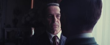 Movie still from “Neruda” (2016), directed by Pablo Larraín – An older man wearing a suit and tie; Close Up shot, Over the shoulder angle
