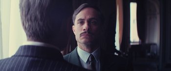 Movie still from “Neruda” (2016), directed by Pablo Larraín – A person wearing a suit and tie; Close Up shot, Over the shoulder angle