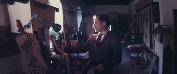 Movie still from “Neruda” (2016), directed by Pablo Larraín – A man standing in front of an easel in a room; Medium shot, Low angle