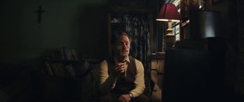 Movie still from “Neruda” (2016), directed by Pablo Larraín – A man sitting in a chair with a cigarette in his mouth; Medium shot, Low angle
