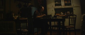 Movie still from “Neruda” (2016), directed by Pablo Larraín – A man sitting at a dining room table typing on a typewriter; Medium shot, Low angle