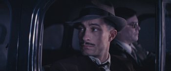 Movie still from “Neruda” (2016), directed by Pablo Larraín – A man in a hat and a suit sitting in a car; Close Up shot, High angle