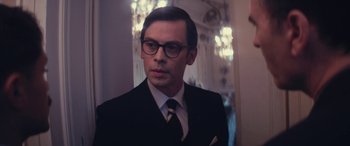 Movie still from “Neruda” (2016), directed by Pablo Larraín – A man in a suit and tie wearing glasses; Close Up shot, Low angle