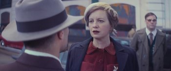Movie still from “Neruda” (2016), directed by Pablo Larraín – An older woman wearing a hat talking to a younger man; Close Up shot, Over the shoulder angle