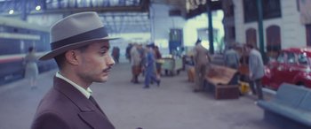 Movie still from “Neruda” (2016), directed by Pablo Larraín – A man in a hat and a suit standing in front of a crowd; Close Up shot, Over the shoulder angle