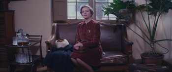 Movie still from “Neruda” (2016), directed by Pablo Larraín – A woman sitting on top of a brown leather couch; Medium shot, Low angle