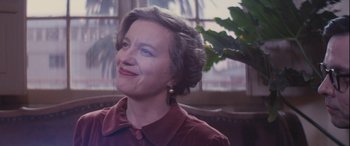 Movie still from “Neruda” (2016), directed by Pablo Larraín – An older woman is smiling while sitting in a chair; Close Up shot, Over the shoulder angle