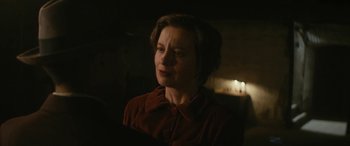 Movie still from “Neruda” (2016), directed by Pablo Larraín – A woman in a red shirt is standing in a dark room; Close Up shot, Over the shoulder angle