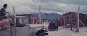 Movie still from “Neruda” (2016), directed by Pablo Larraín – A group of people riding in a truck down a dirt road; Extreme Wide shot, High angle