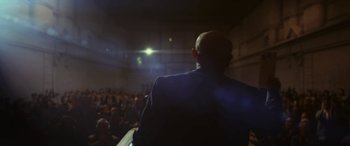 Movie still from “Neruda” (2016), directed by Pablo Larraín – A man in a suit is standing in front of an audience; Medium shot, Low angle