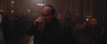 Movie still from “Neruda” (2016), directed by Pablo Larraín – A man drinking a glass of beer in a dark room; Medium shot, High angle