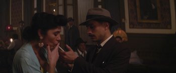 Movie still from “Neruda” (2016), directed by Pablo Larraín – A man in a suit and a hat smoking a cigarette; Medium shot, Over the shoulder angle