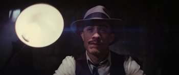 Movie still from “Neruda” (2016), directed by Pablo Larraín – A man in a hat and a tie looking at the camera; Close Up shot, Low angle