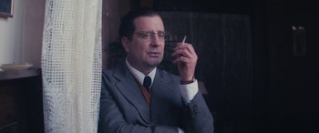 Movie still from “Neruda” (2016), directed by Pablo Larraín – A man in a suit and tie smoking a cigarette; Close Up shot, Over the shoulder angle