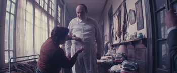 Movie still from “Neruda” (2016), directed by Pablo Larraín – An older man standing next to an older woman in a room; Medium shot, Low angle