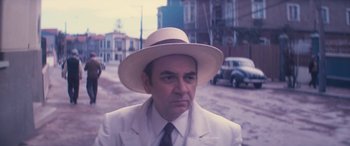 Movie still from “Neruda” (2016), directed by Pablo Larraín – An older man wearing a white suit and a hat; Close Up shot, Low angle