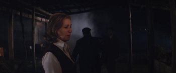 Movie still from “Neruda” (2016), directed by Pablo Larraín – A woman standing in front of a group of people; Medium shot, Over the shoulder angle