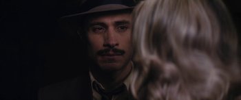 Movie still from “Neruda” (2016), directed by Pablo Larraín – A person wearing a suit and hat; Close Up shot, Over the shoulder angle
