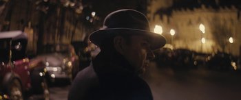 Movie still from “Neruda” (2016), directed by Pablo Larraín – A man wearing a hat standing on a street; Close Up shot, Low angle