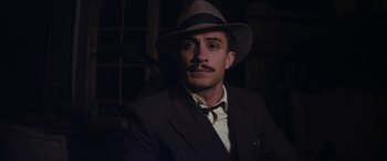 Movie still from “Neruda” (2016), directed by Pablo Larraín – A man wearing a suit and a hat; Close Up shot, Low angle