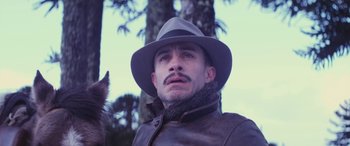 Movie still from “Neruda” (2016), directed by Pablo Larraín – A man in a hat and a leather jacket with a cat; Close Up shot, Low angle