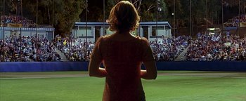 Movie still from “Never Been Kissed” (1999), directed by Raja Gosnell – A woman standing in front of an audience on a field; Wide shot, Over the shoulder angle