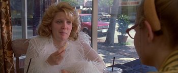 Movie still from “Never Been Kissed” (1999), directed by Raja Gosnell – A woman sitting in front of a window eating a donut; Close Up shot, Low angle