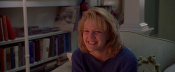 Movie still from “Never Been Kissed” (1999), directed by Raja Gosnell – A woman smiling for the camera while sitting in a chair; Close Up shot, Low angle