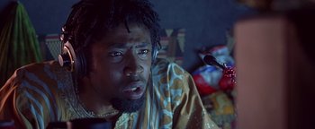 Movie still from “Never Been Kissed” (1999), directed by Raja Gosnell – A man with dreadlocks wearing headphones sitting in front of a microphone; Close Up shot, Low angle