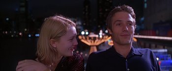 Movie still from “Never Been Kissed” (1999), directed by Raja Gosnell – A man and a woman smiling at each other in front of lights; Medium shot, Over the shoulder angle