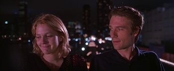 Movie still from “Never Been Kissed” (1999), directed by Raja Gosnell – A man and a woman sitting next to each other in front of a city skyline at night; Medium shot, Over the shoulder angle
