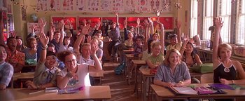 Movie still from “Never Been Kissed” (1999), directed by Raja Gosnell – A group of people sitting in a classroom raising their hands; Wide shot, High angle