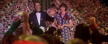Movie still from “Never Been Kissed” (1999), directed by Raja Gosnell – A man and a woman standing next to each other in front of flowers; Medium shot, Low angle