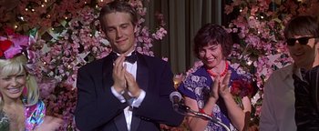 Movie still from “Never Been Kissed” (1999), directed by Raja Gosnell – A man and a woman clapping in front of microphones; Close Up shot, Over the shoulder angle