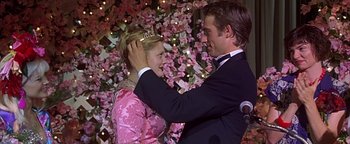 Movie still from “Never Been Kissed” (1999), directed by Raja Gosnell – A man and a woman in formal wear touching their heads; Medium shot, Over the shoulder angle