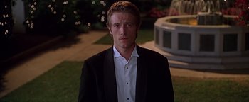 Movie still from “Never Been Kissed” (1999), directed by Raja Gosnell – A young man in a suit standing in front of a fountain; Close Up shot, Over the shoulder angle