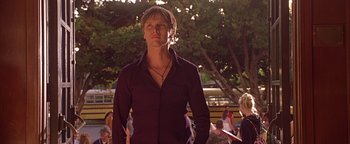 Movie still from “Never Been Kissed” (1999), directed by Raja Gosnell – A man in a purple shirt is standing in front of a tree; Medium shot, Low angle