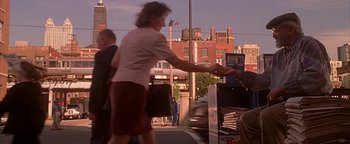 Movie still from “Never Been Kissed” (1999), directed by Raja Gosnell – A woman is handing a card to someone else; Wide shot, High angle