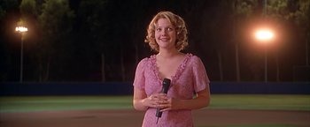 Movie still from “Never Been Kissed” (1999), directed by Raja Gosnell – A woman in a pink dress is holding a microphone; Medium shot, Low angle